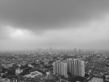 High angle view of city buildings against cloudy sky