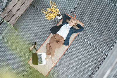 Businesswoman lying on desk with laptop in office