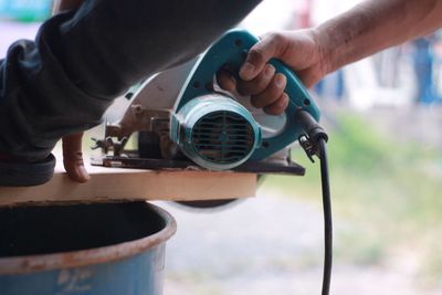 Cropped hands of man cutting wood at workshop