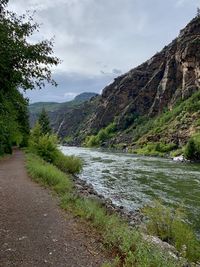 Scenic view of river by mountains against sky