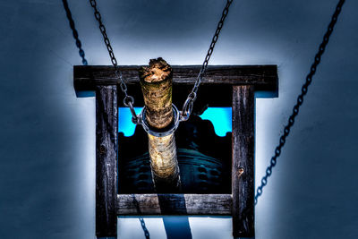 Close-up of rope tied up on metal chain against blue sky