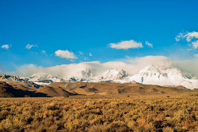 Scenic view of landscape and mountains against blue sky