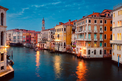 Venice's grand canal at sunset with illuminated historic buildings and light trails of tourist boats