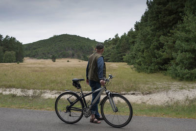 Rear view of man riding bicycle on field