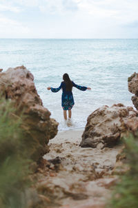 Rear view of man standing on rock at beach