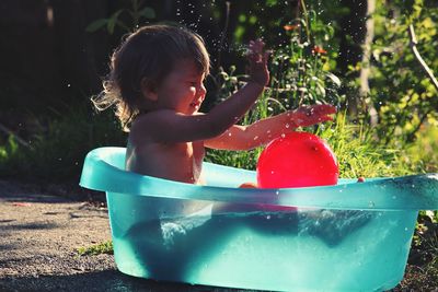 Toddler playing with ball in blue wading pool at yard