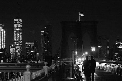 Silhouette people walking on brooklyn bridge in city at night