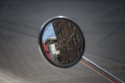 Close-up of reflection of bare trees and building in side-view mirror