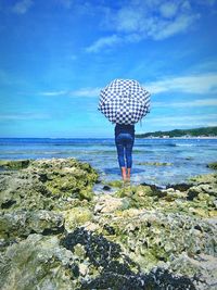 Rear view of woman standing by sea against sky