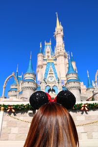 Rear view of woman standing outside cathedral against clear blue sky