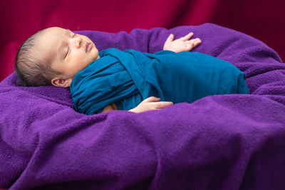 Cute newborn baby sleeping in baby wrap flat angle shot