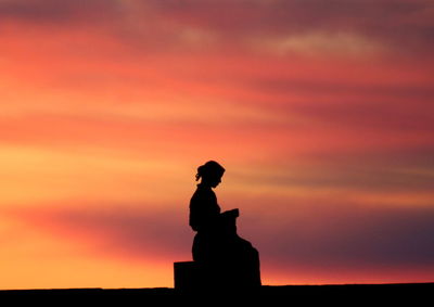 Silhouette man standing against orange sky