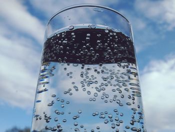 Close-up of wet glass against blue sky