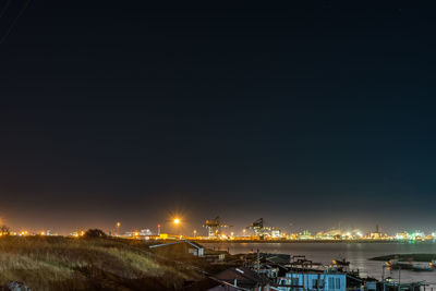 Illuminated harbor against sky at night