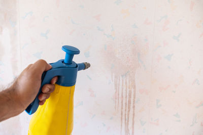 Midsection of man holding umbrella against wall at home