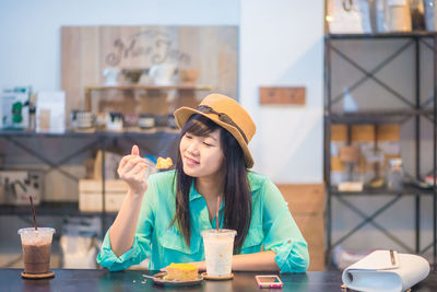 Portrait of young woman holding ice cream in cafe