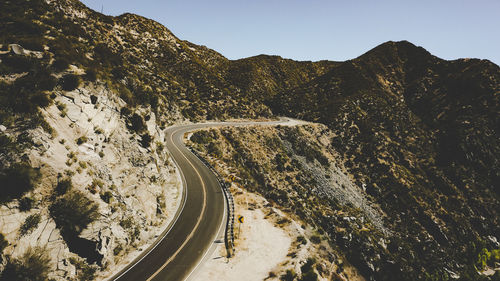 Road by mountains against clear sky