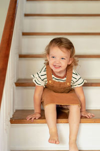 Smiling girl sitting on staircase at home