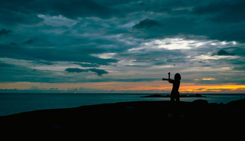 Silhouette woman workout in the morning at stone beach with beautiful sunrise sky. fit woman.