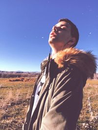 Man looking away while standing on field against sky