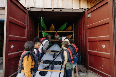 Kids loading kayak in cargo container with counselors at summer camp