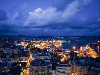 Illuminated cityscape against cloudy sky