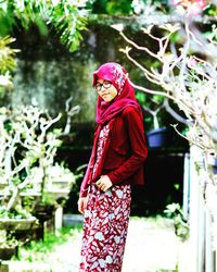 Young woman standing by tree