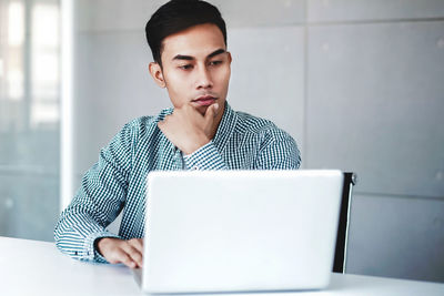 Young man using mobile phone while sitting on table