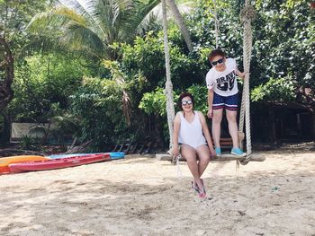 Portrait of happy friends swinging at beach