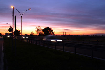 View of vehicles on road at sunset