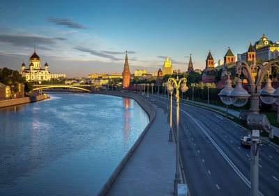 Bridge over river by buildings against sky in city