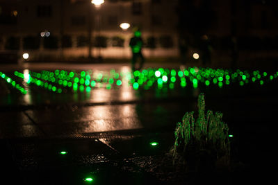 Illuminated lights on wet street at night