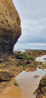 Rock formation on beach against sky