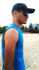 Side view of young man wearing sunglasses standing at beach