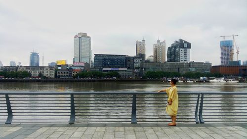 Side view of woman standing by river in city