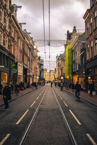 Road by buildings in city against sky