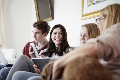 Smiling children using technologies while sitting with mother at home