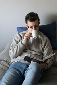 Young woman using mobile phone while sitting on sofa at home