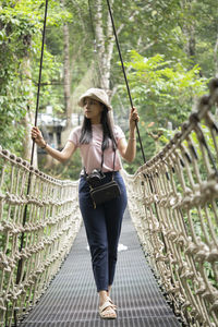 Full length of woman standing on rope against trees