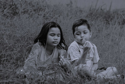 Siblings sitting on grass in public park