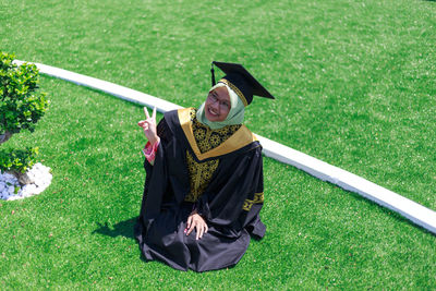 Portrait of smiling young woman standing on green field