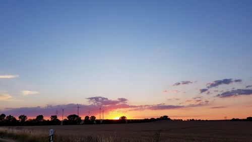 Silhouette people on field against sky during sunset
