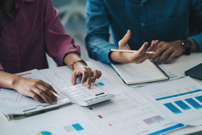 Midsection of business people working on table