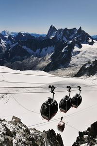 Low angle view of overhead cable car against snowcapped mountains