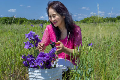 Woman holding purple flowering plants on field