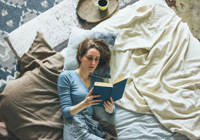 Full length of woman using mobile phone while relaxing on bed