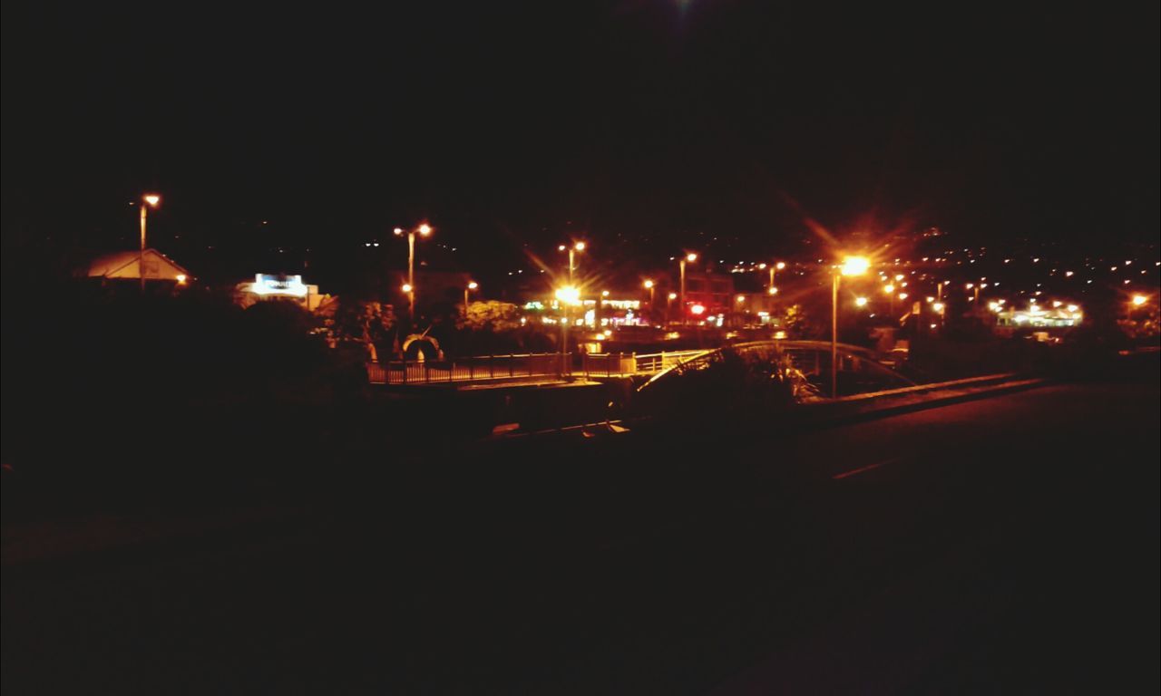 illuminated, night, street light, transportation, lighting equipment, car, street, land vehicle, city, mode of transport, road, copy space, building exterior, clear sky, dark, light - natural phenomenon, traffic, city street, city life, sky