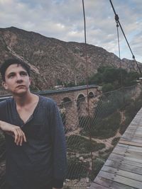 Young man standing on mountain against sky