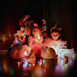 Portrait of cute friends with illuminated lights sitting on floor 