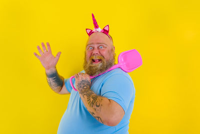 Portrait of man standing against yellow background